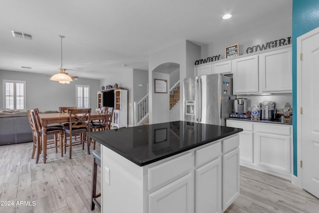 kitchen featuring light wood-type flooring, pendant lighting, a center island, stainless steel refrigerator with ice dispenser, and white cabinets