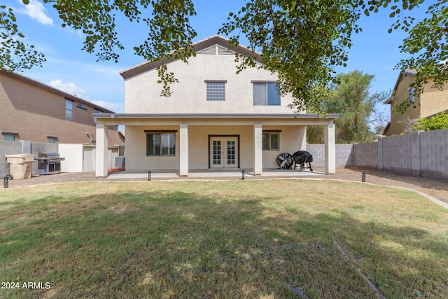 rear view of house featuring french doors, a lawn, and a patio