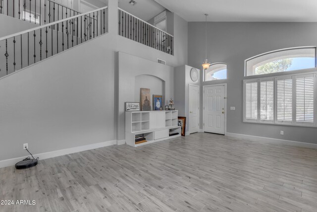 living room featuring a notable chandelier, high vaulted ceiling, and light hardwood / wood-style floors