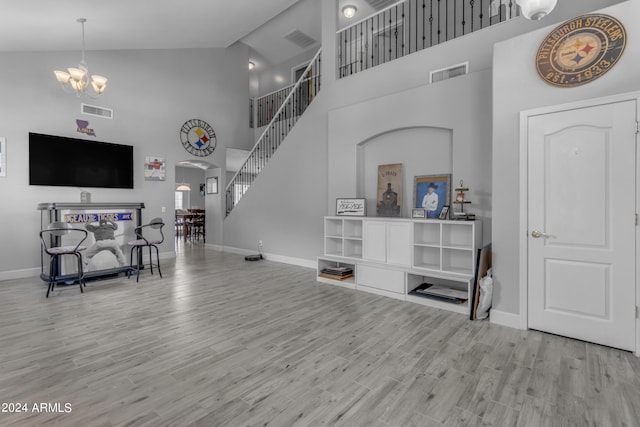 living room featuring high vaulted ceiling, a notable chandelier, and light wood-type flooring