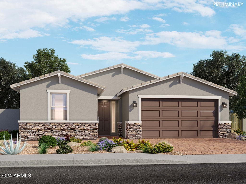 ranch-style home featuring a garage, stone siding, and stucco siding