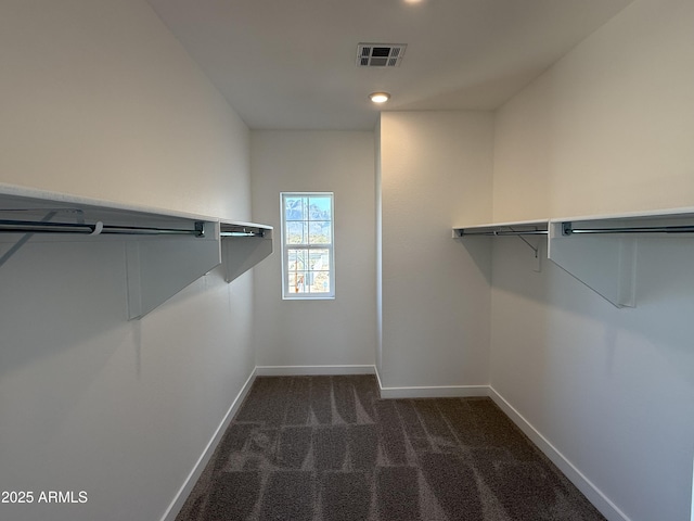 spacious closet featuring dark colored carpet and visible vents