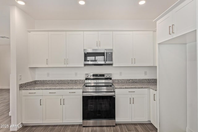 kitchen with appliances with stainless steel finishes, light stone counters, wood finish floors, white cabinetry, and recessed lighting