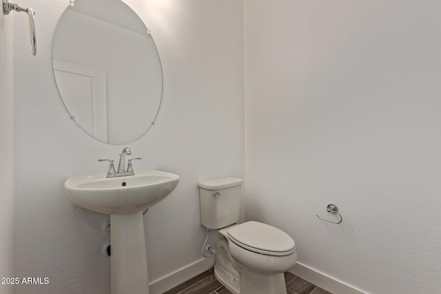 bathroom with baseboards, toilet, and wood finished floors