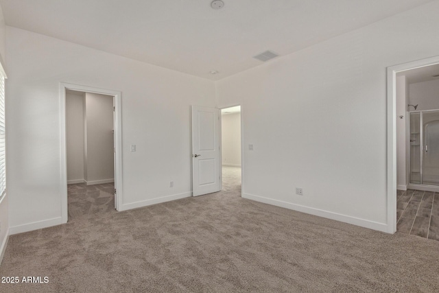 unfurnished bedroom with ensuite bathroom, carpet flooring, visible vents, and baseboards