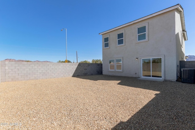 rear view of property with cooling unit, a fenced backyard, and stucco siding