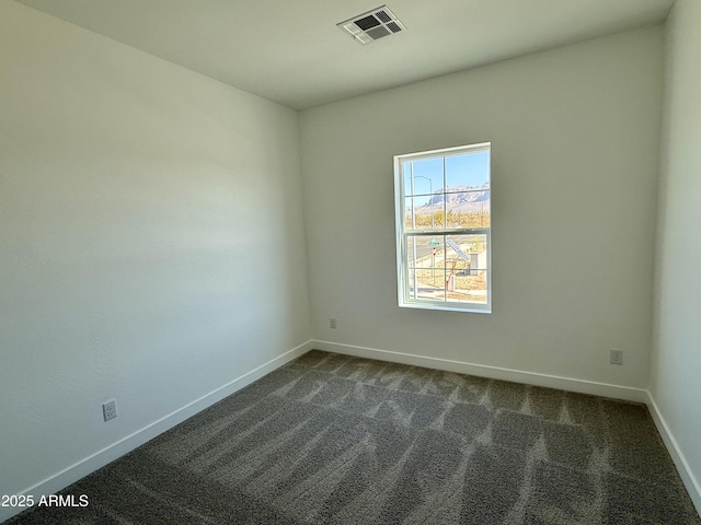 spare room featuring dark colored carpet, visible vents, and baseboards