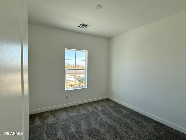 unfurnished room featuring dark colored carpet, visible vents, and baseboards