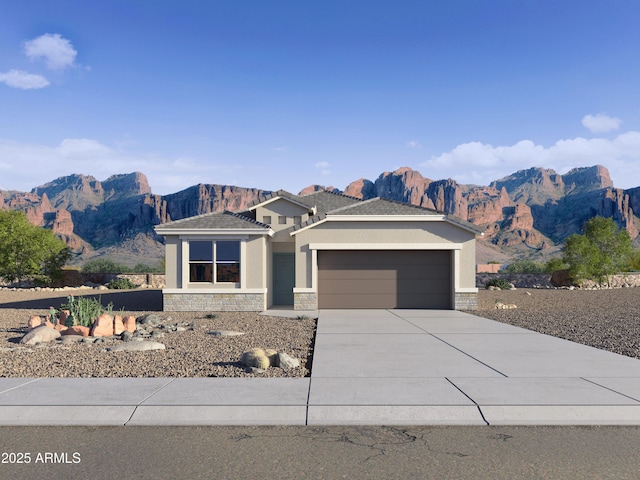 prairie-style house featuring a mountain view, a garage, driveway, stone siding, and stucco siding