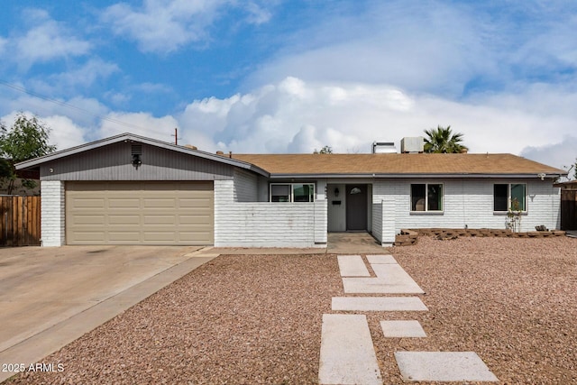 ranch-style home with an attached garage, fence, concrete driveway, and brick siding