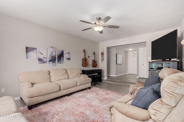 living room featuring a ceiling fan, baseboards, visible vents, and wood finished floors