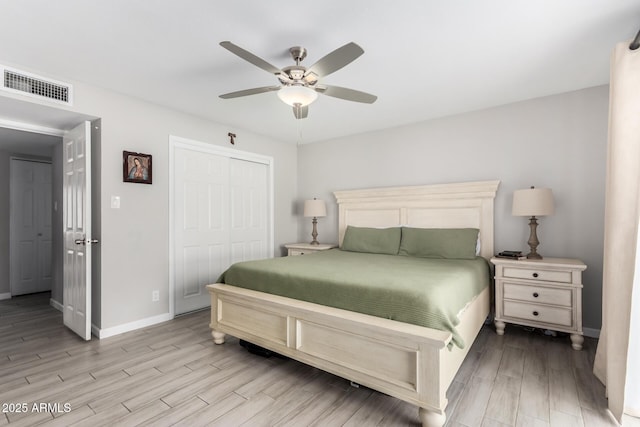 bedroom featuring light wood-style floors, baseboards, visible vents, and a closet