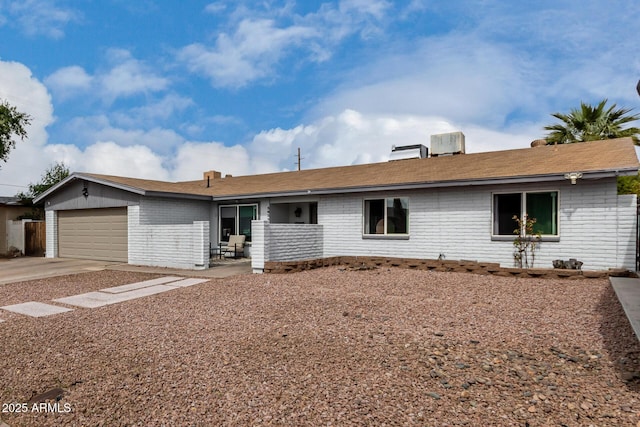 ranch-style house featuring concrete driveway, brick siding, an attached garage, and central air condition unit