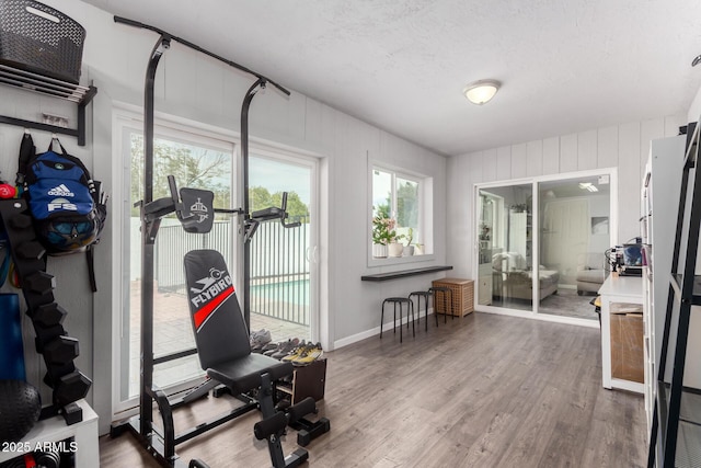 exercise area with a textured ceiling, baseboards, and wood finished floors