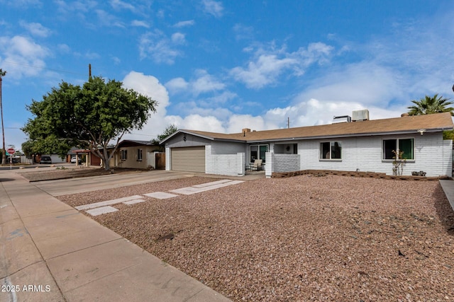 ranch-style house featuring concrete driveway, brick siding, and an attached garage