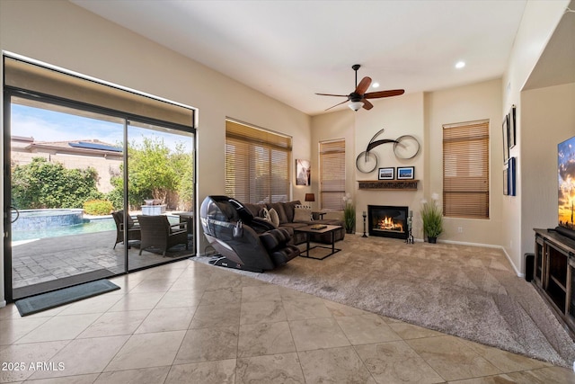 carpeted living room with a glass covered fireplace, ceiling fan, tile patterned flooring, recessed lighting, and baseboards