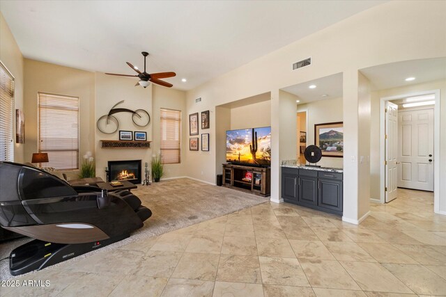 living area featuring a ceiling fan, a glass covered fireplace, baseboards, and recessed lighting