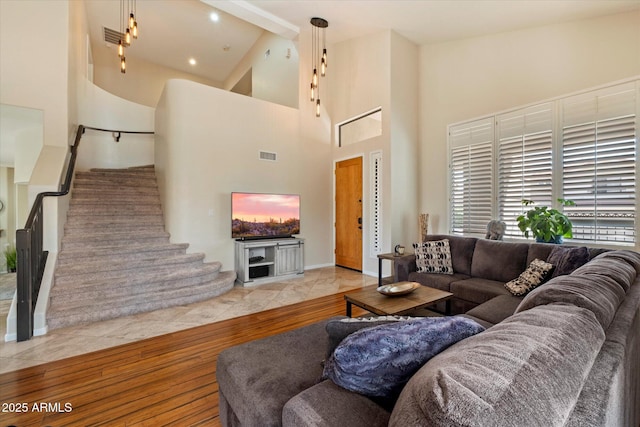 living area featuring stairs, wood finished floors, and high vaulted ceiling