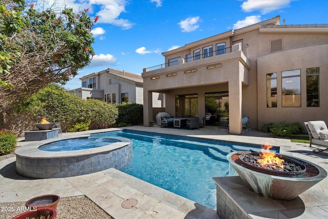 back of property featuring a fire pit, a patio, stucco siding, and a pool with connected hot tub