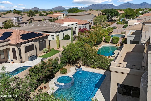 view of pool featuring a residential view, a mountain view, a pool with connected hot tub, and a patio