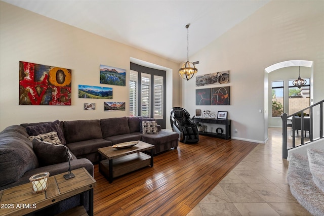 living area with a chandelier, plenty of natural light, stairway, arched walkways, and high vaulted ceiling