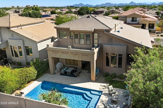 rear view of property featuring a balcony, stucco siding, a mountain view, a patio, and a residential view
