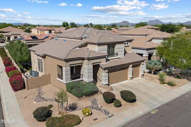 view of front facade featuring stucco siding, a balcony, a tile roof, an attached garage, and central AC