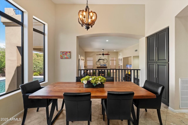 dining space featuring arched walkways, baseboards, a chandelier, ceiling fan, and light tile patterned floors