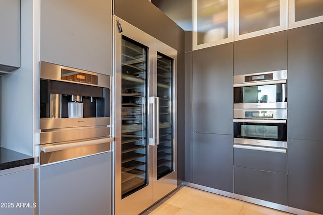 kitchen featuring stainless steel double oven, beverage cooler, and light tile patterned floors