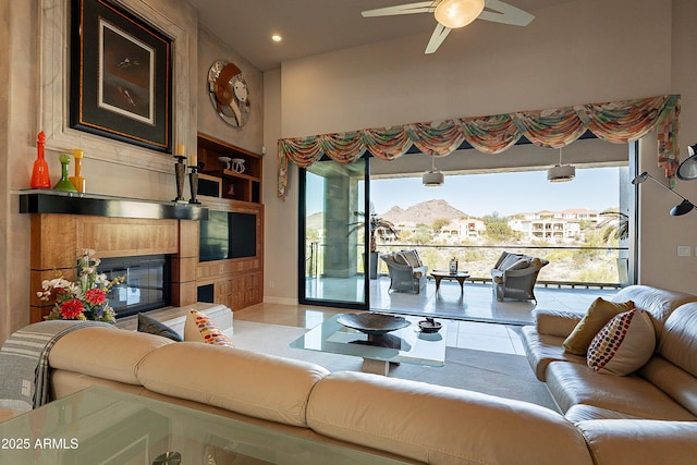 tiled living room featuring ceiling fan, a large fireplace, and a high ceiling