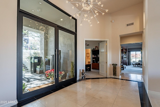 entrance foyer with a notable chandelier, a towering ceiling, and light tile patterned flooring