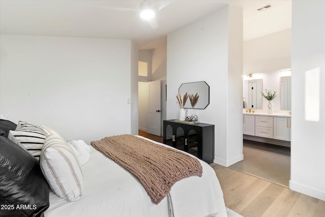 bedroom featuring connected bathroom, light hardwood / wood-style flooring, and a high ceiling