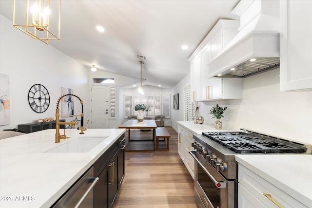 kitchen with stainless steel appliances, custom exhaust hood, sink, and decorative light fixtures