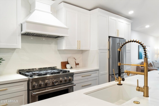 kitchen featuring sink, stainless steel appliances, tasteful backsplash, custom range hood, and white cabinets