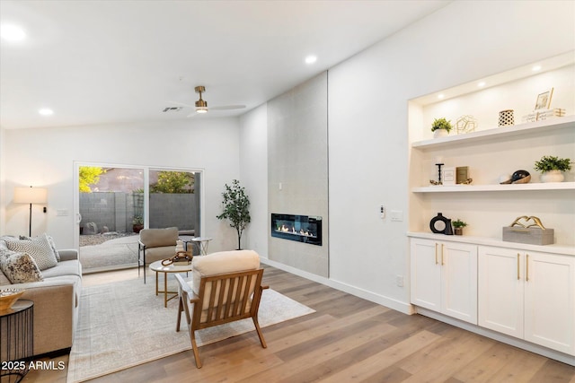 living room with light hardwood / wood-style flooring, a fireplace, ceiling fan, and vaulted ceiling