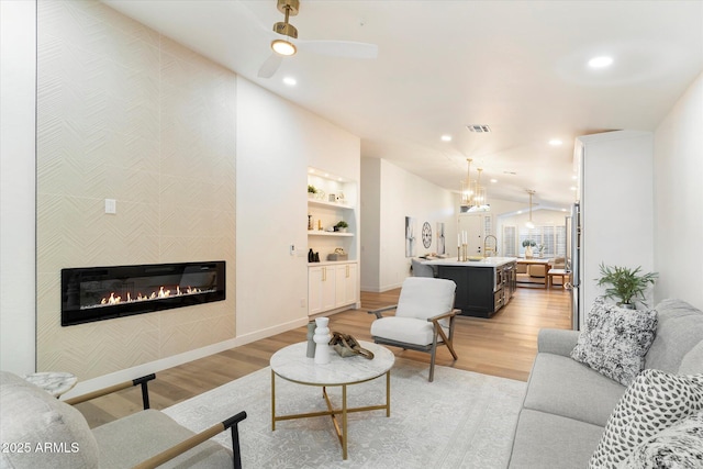 living room with sink, built in features, light hardwood / wood-style flooring, and a tile fireplace