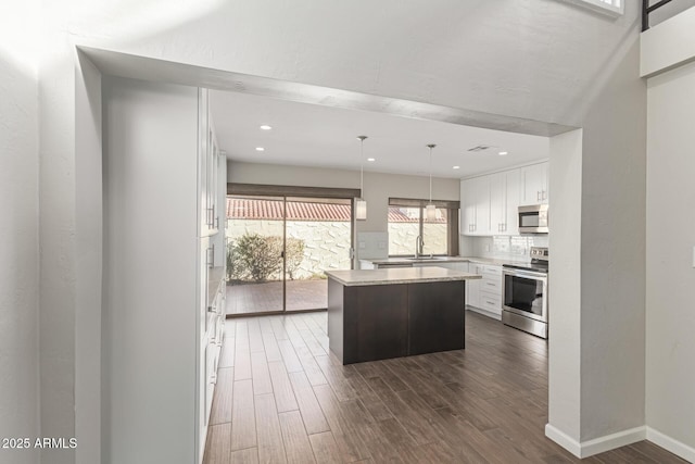 kitchen with a center island, sink, hanging light fixtures, white cabinetry, and stainless steel appliances