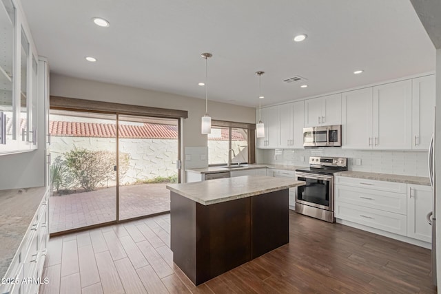 kitchen with white cabinets, a center island, sink, and stainless steel appliances