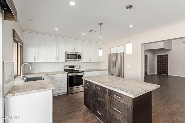 kitchen with pendant lighting, a center island, sink, appliances with stainless steel finishes, and white cabinetry