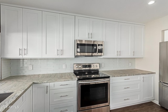 kitchen featuring appliances with stainless steel finishes, tasteful backsplash, white cabinetry, and light stone counters