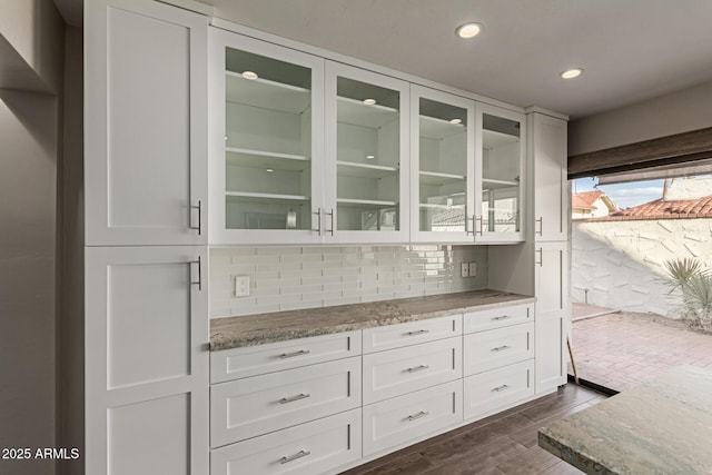 bar with backsplash, white cabinetry, and light stone counters