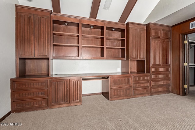 unfurnished office with light colored carpet, lofted ceiling, and built in desk