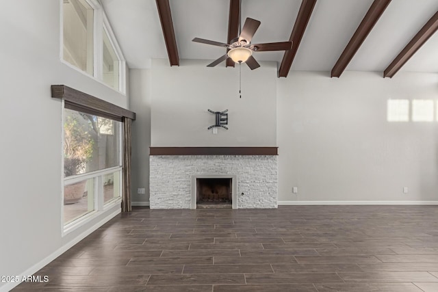 unfurnished living room with ceiling fan, beam ceiling, and a stone fireplace