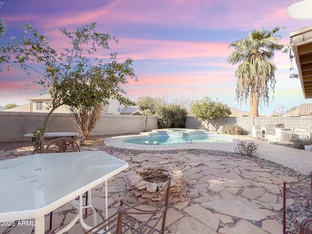 pool at dusk with a patio and area for grilling