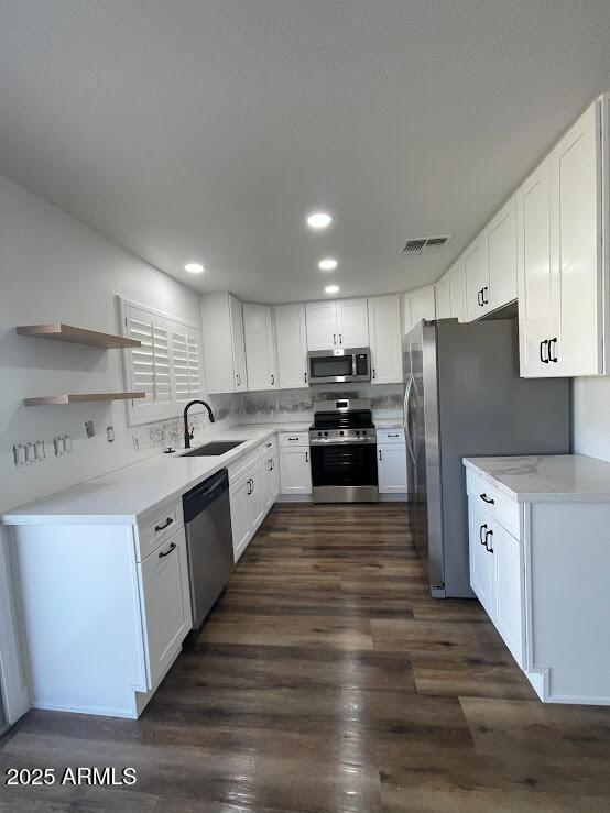 kitchen with white cabinets, appliances with stainless steel finishes, tasteful backsplash, sink, and dark hardwood / wood-style floors