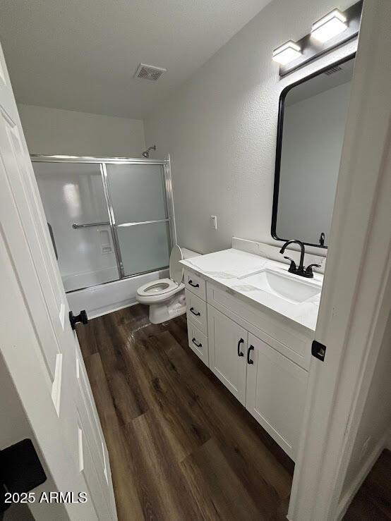 full bathroom with vanity, toilet, bath / shower combo with glass door, and hardwood / wood-style floors