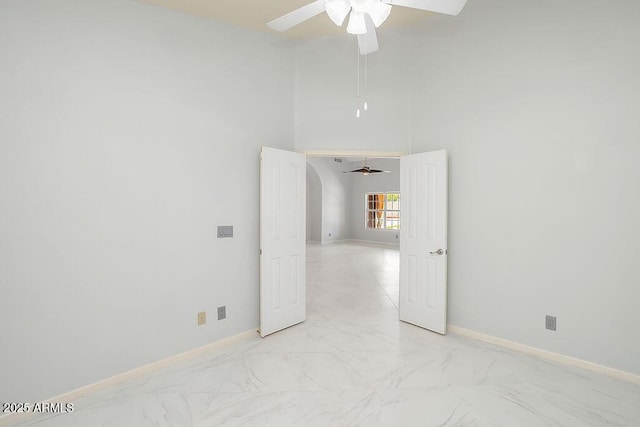 16219 S 14th Way, Phoenix, AZ 85048 - empty room with a ceiling fan, light marble finish flooring, baseboards, arched walkways, and a high ceiling