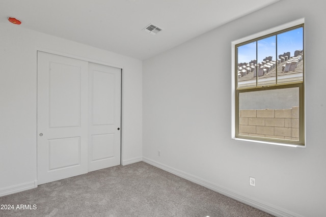 unfurnished bedroom featuring a closet and light colored carpet