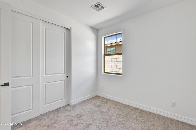 unfurnished bedroom with light carpet and a closet