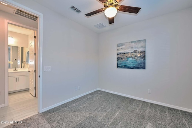 unfurnished room with sink, light colored carpet, and ceiling fan